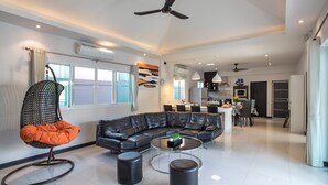Una sala de estar moderna con un sofá modular, un sillón colgante y una mesa de centro redonda.