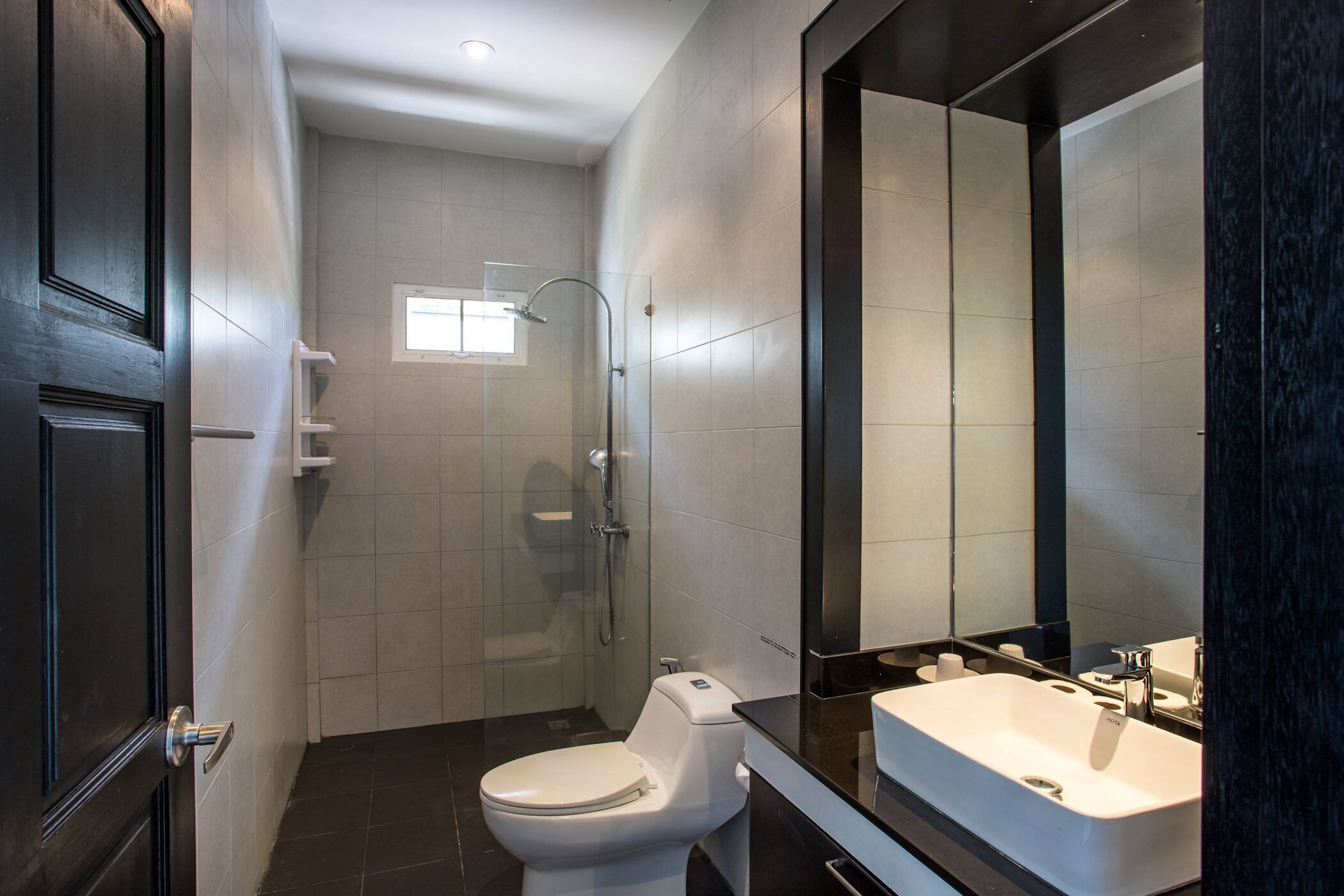 A modern bathroom with a toilet, shower, and sink.