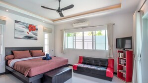 Un dormitorio moderno con una cama grande, un sofá, un televisor y una estantería.