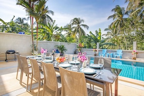 A poolside dining area with wicker chairs, a table set for six, and a view of the pool. - Tropical Vibe 5BR Pool Villa Nikkie 3 (Rawai)