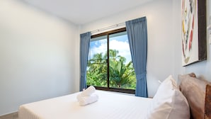 A hotel room with a bed, a window with curtains, and a view of palm trees. - Tropical Vibe 5BR Pool Villa Nikkie 3 (Rawai)