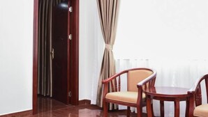 A room with a wooden door, beige curtains, and a round wooden table with two chairs. - Hao Ye Hotel (Yangjiang)