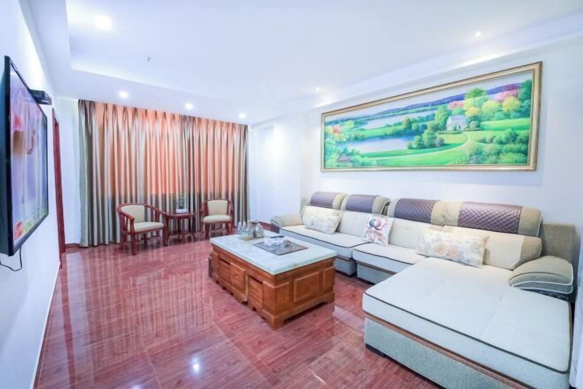 A living room with a sofa set, a wooden coffee table, and a painting on the wall.