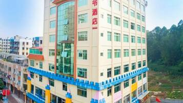 A multi-story hotel with a prominent red sign on the facade, multiple windows, and a blue and yellow lower level.