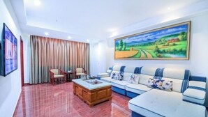 A living room with a sofa, chairs, a coffee table, and a painting on the wall. - Hao Ye Hotel (Yangjiang)