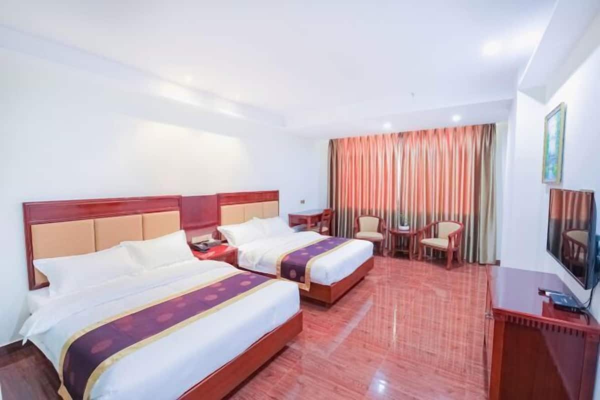 A hotel room with two beds, a desk, a chair, a TV, and a window with curtains.