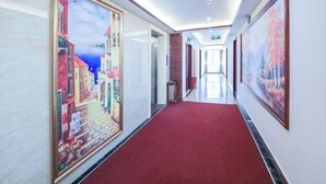 A hallway with a red carpet, framed artwork on the walls, and a view into another room. - Hao Ye Hotel (Yangjiang)