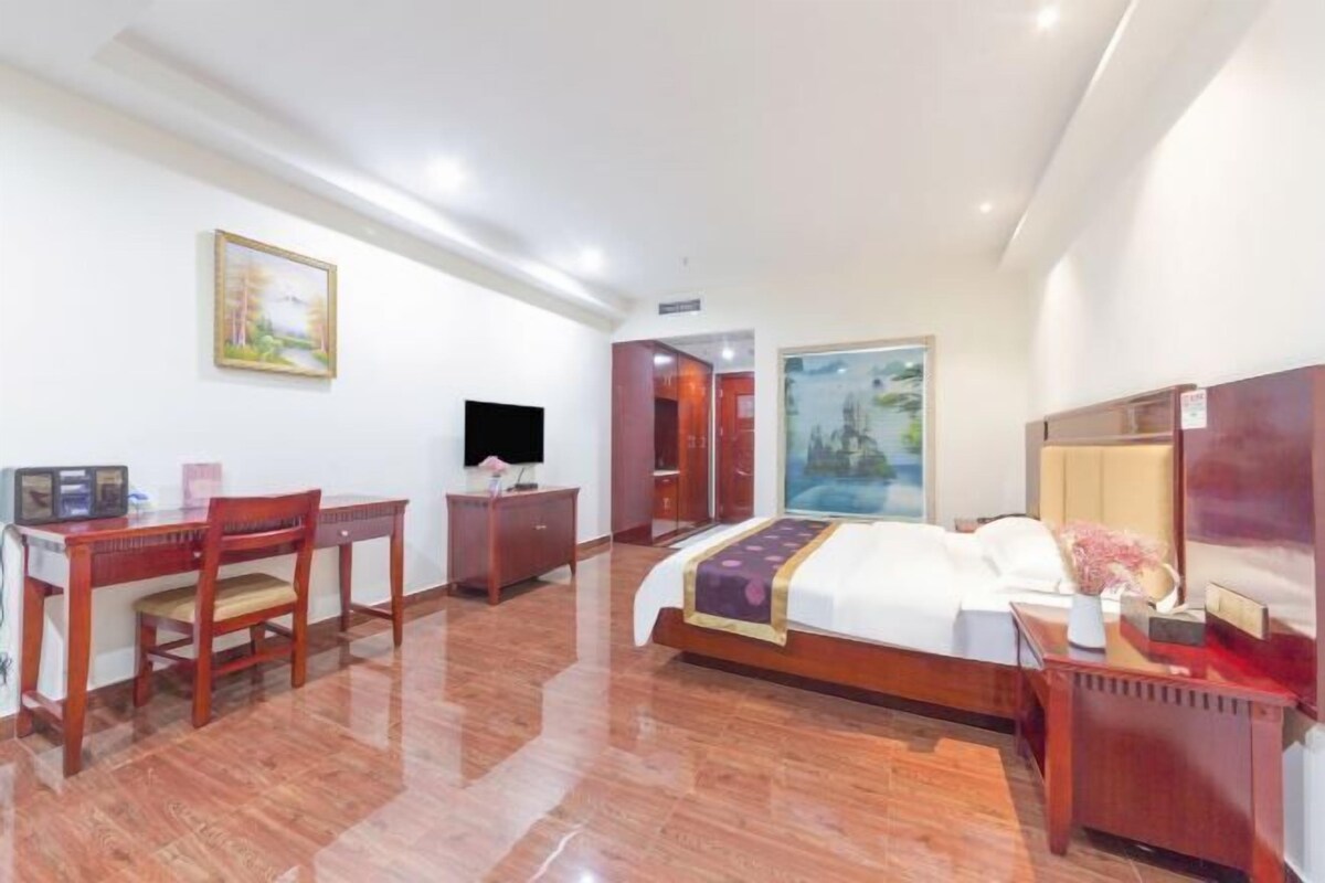 Ein Hotelzimmer mit einem Bett, einem Schreibtisch, einem Sessel, einem Fernseher und Bildern an den Wänden.