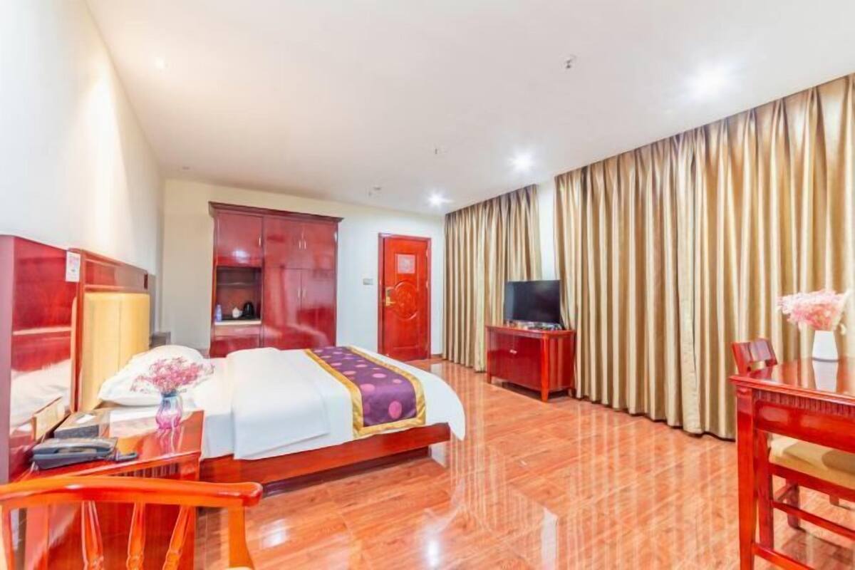 A hotel room with a bed, a TV, a desk, and a chair.