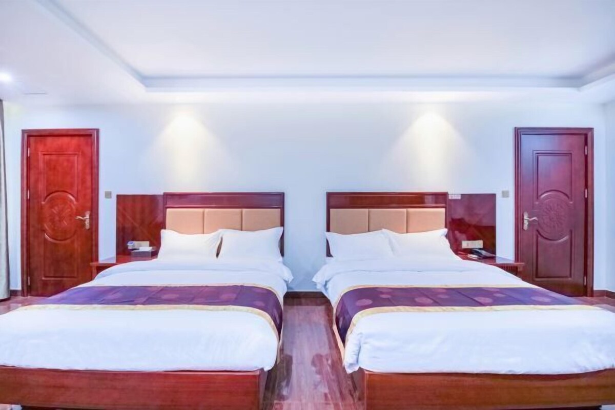 Ein Hotelzimmer mit zwei Betten, Holz-Kopfteilen und Holzboden.