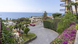 A residential area with a curved road, a red car parked on the side, and a view of the sea in the background. - Blu oltremare by Interhome (Sanremo)