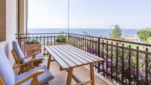 A balcony with a wooden table and chairs, potted plants, and a view of the sea. - Blu oltremare by Interhome (Sanremo)