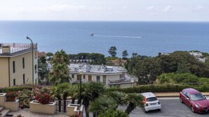 A coastal view with a building, parked cars, and a boat on the sea. - Blu oltremare by Interhome (Sanremo)