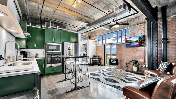 Una cocina moderna con gabinetes verdes, electrodomésticos de acero inoxidable y una zona de bar.