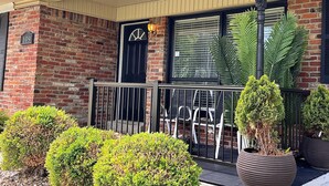 A brick building with a black door, a porch with a railing, and an American flag. - The Nantucket Suites  (Elizabethtown)