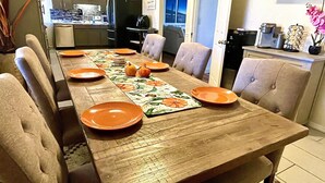 A dining table set with orange plates, a floral placemat, and a small pumpkin centerpiece. - The Nantucket Suites  (Elizabethtown)