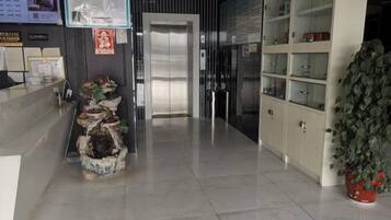 Un área de recepción con mostrador, una planta, un tablero de menú en la pared y un conjunto de armarios.