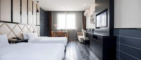 A hotel room with two beds, a desk, a chair, a TV, and a window with curtains.