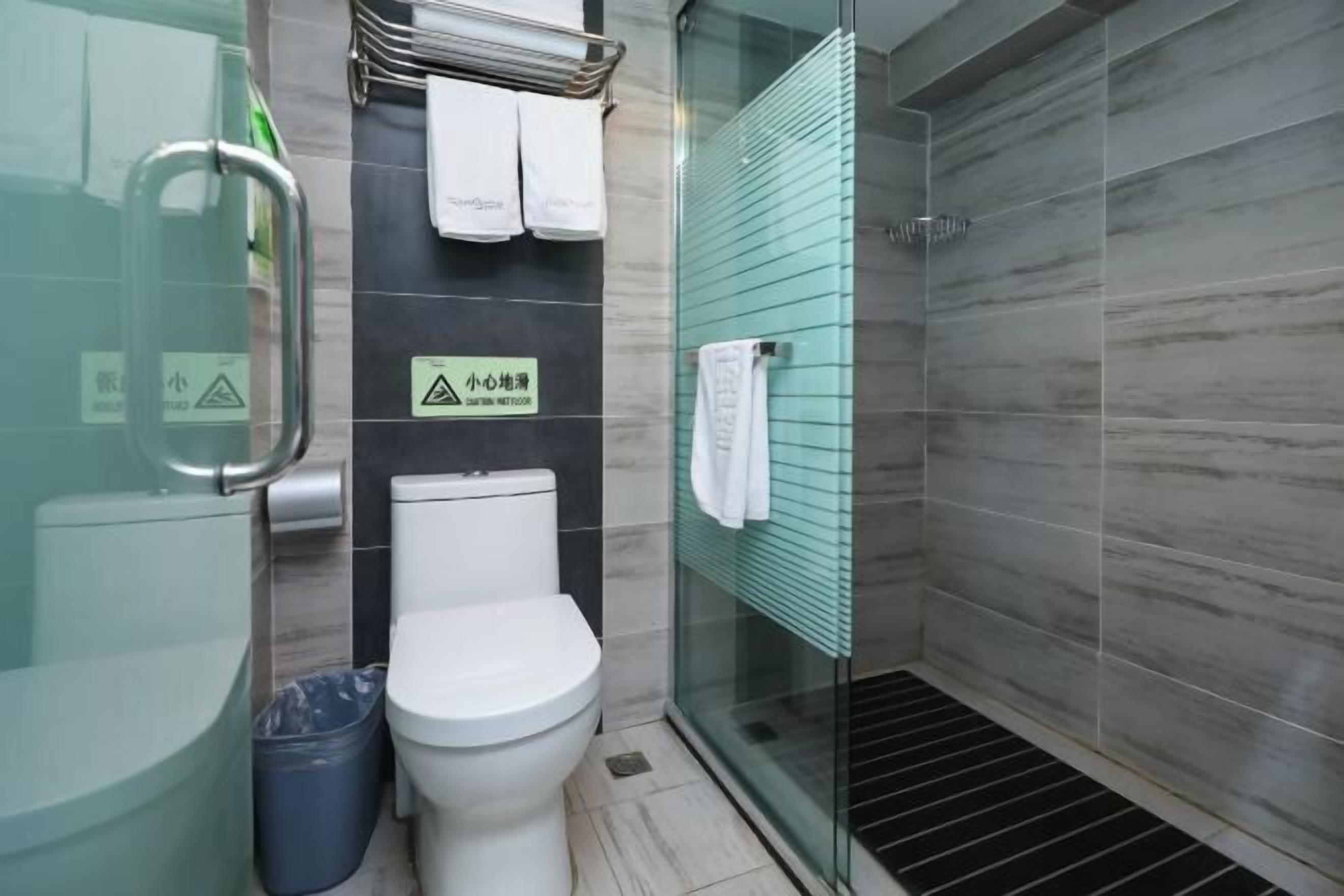 Ein modernes Badezimmer mit Duschkabine aus Glas, Toilette und Mülleimer.