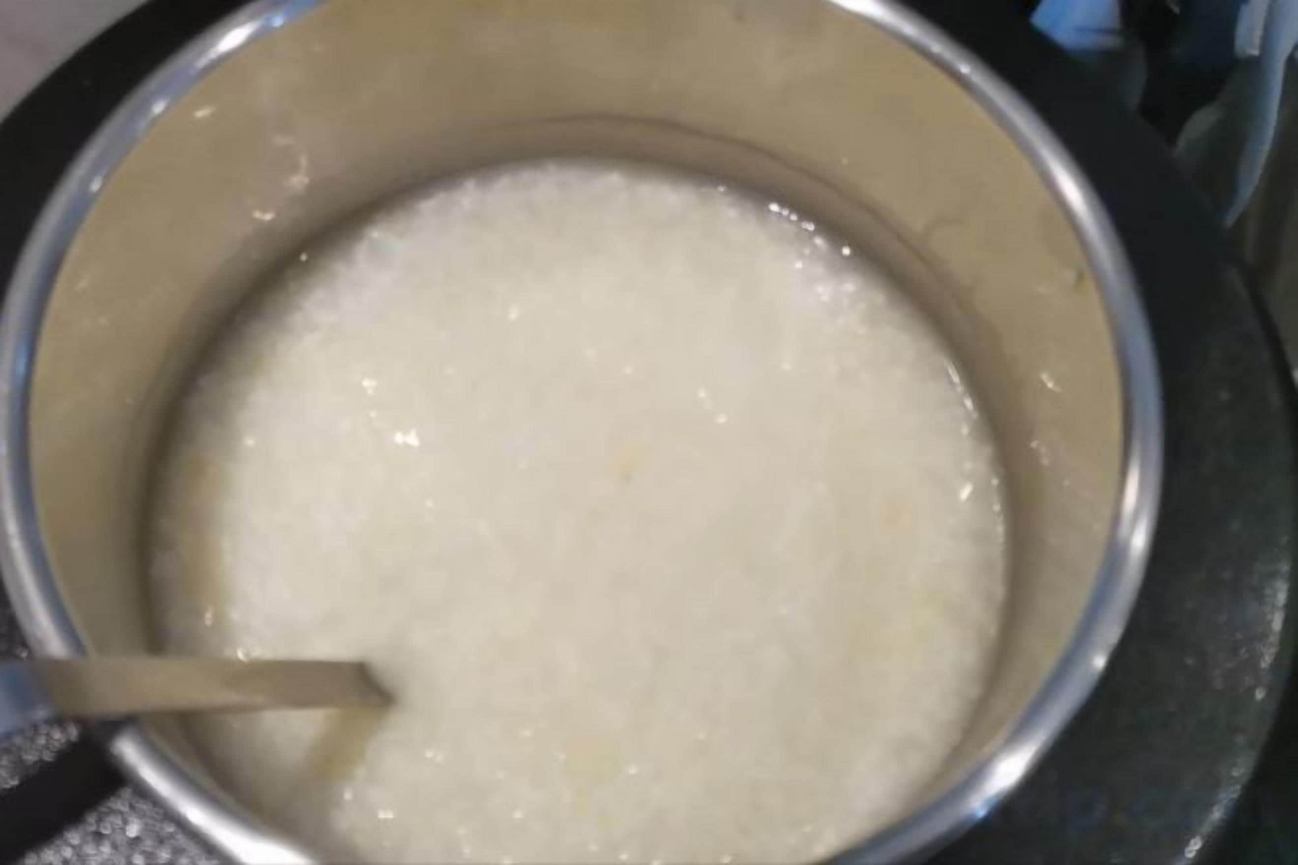 Une casserole contenant un liquide blanc, peut-être une soupe ou une sauce, est en train d’être remuée.
