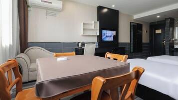 Una habitación de hotel con una mesa de comedor, sillas, un sofá, un televisor y una cama.
