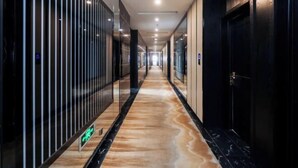 A corridor with a marble floor, glass partitions, and doors on the right. - Qingmu Hotel (Jiangyan Renmin Middle Road Branch) (Taizhou)