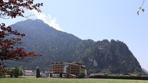 A multi-story building with a traditional architectural style, situated in a grassy field with a mountain backdrop. - Apartment on the outskirts of Strass Zillertal (Strass im Zillertal)