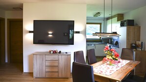 A modern dining area with a wooden table, black chairs, and a flat-screen TV mounted on the wall. - Apartment on the outskirts of Strass Zillertal (Strass im Zillertal)