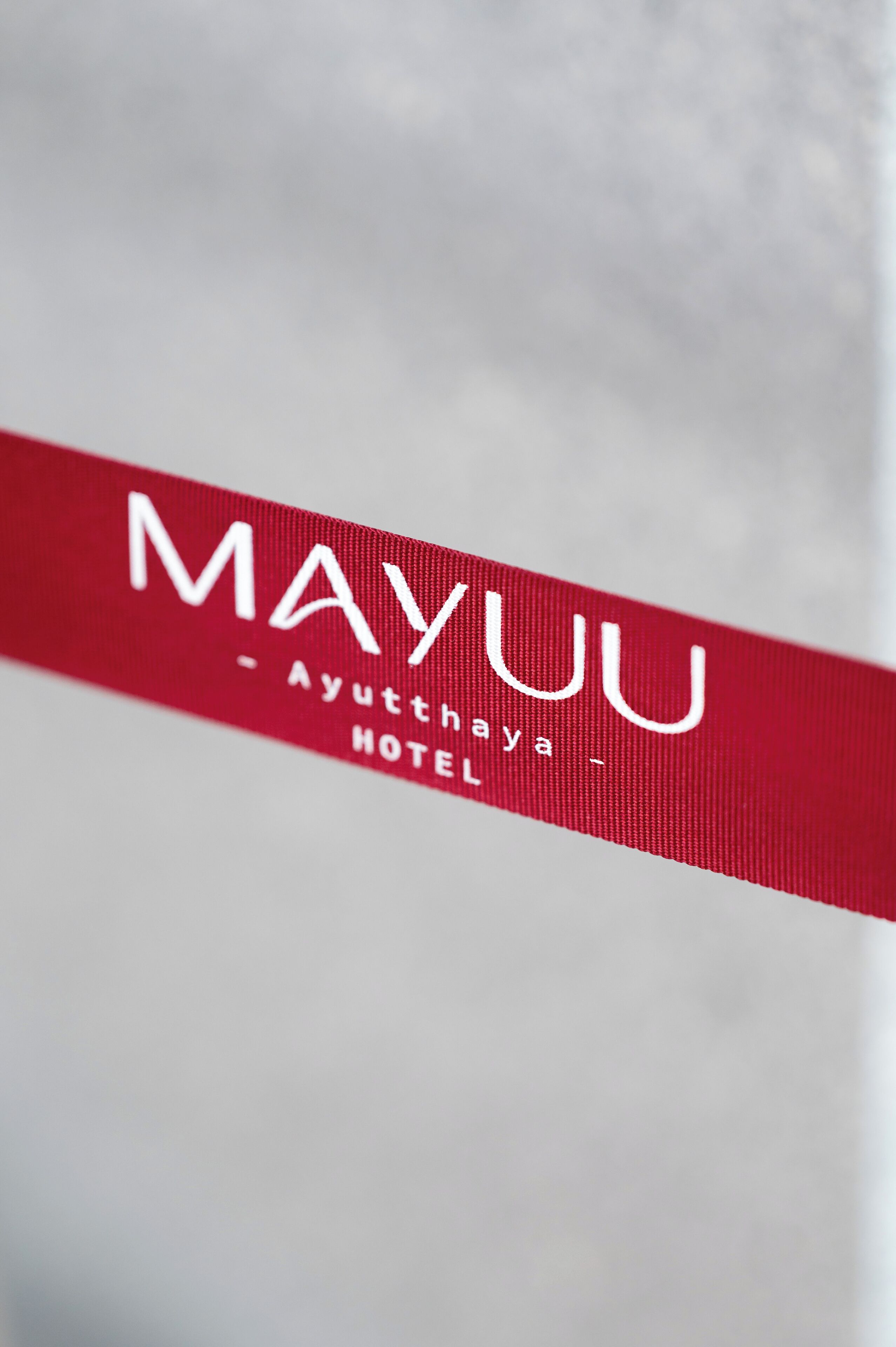 Primer plano de un letrero rojo de hotel con el nombre "MAYUU" y "Ayutthaya Hotel" escritos en él.