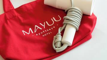 A red bag with "MAYUU - Ayutthaya Hotel" text and a white device with a coiled cable on a white surface.