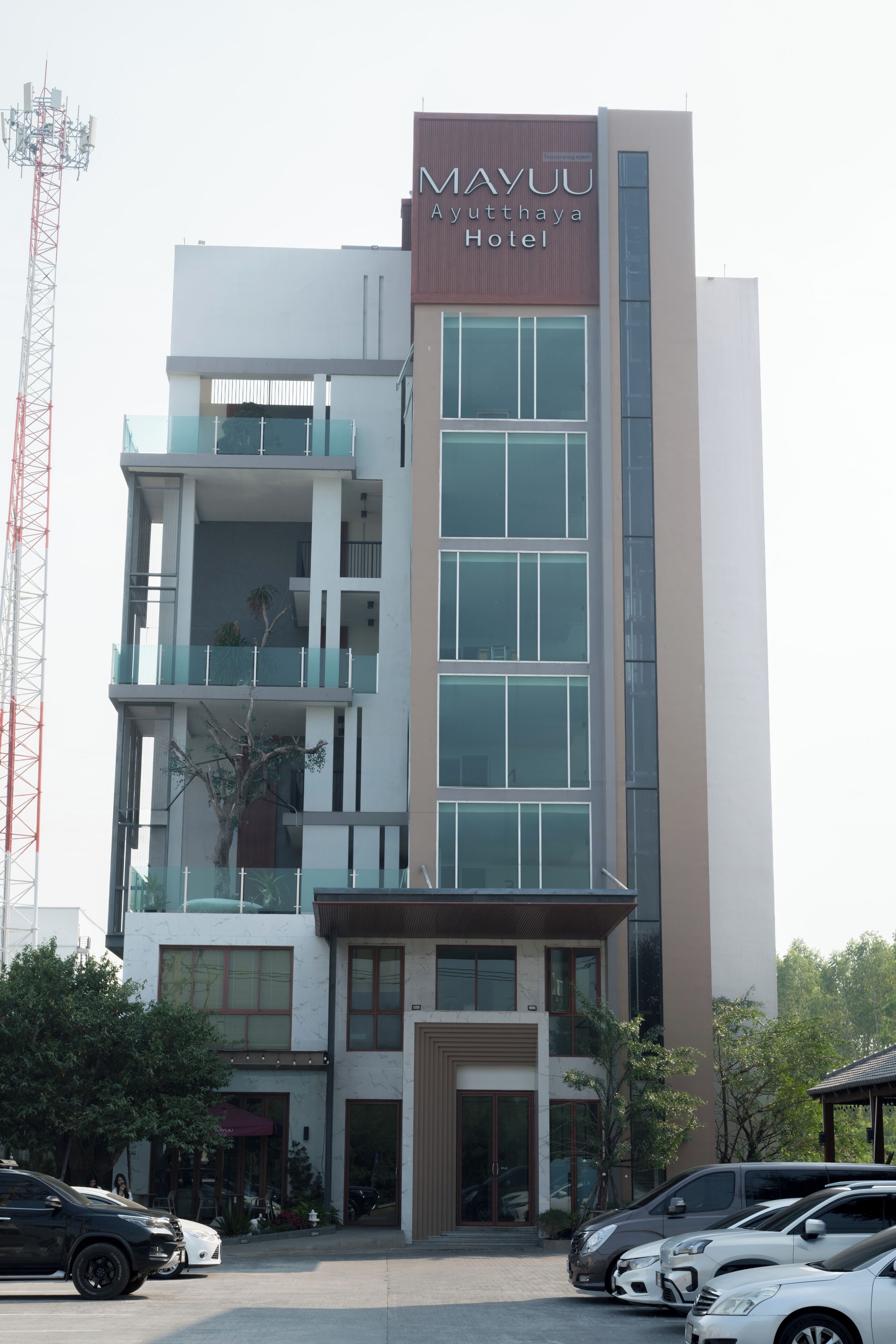 A multi-story hotel with a modern design, featuring a prominent sign for the Mayuu Ayutthaya Hotel.