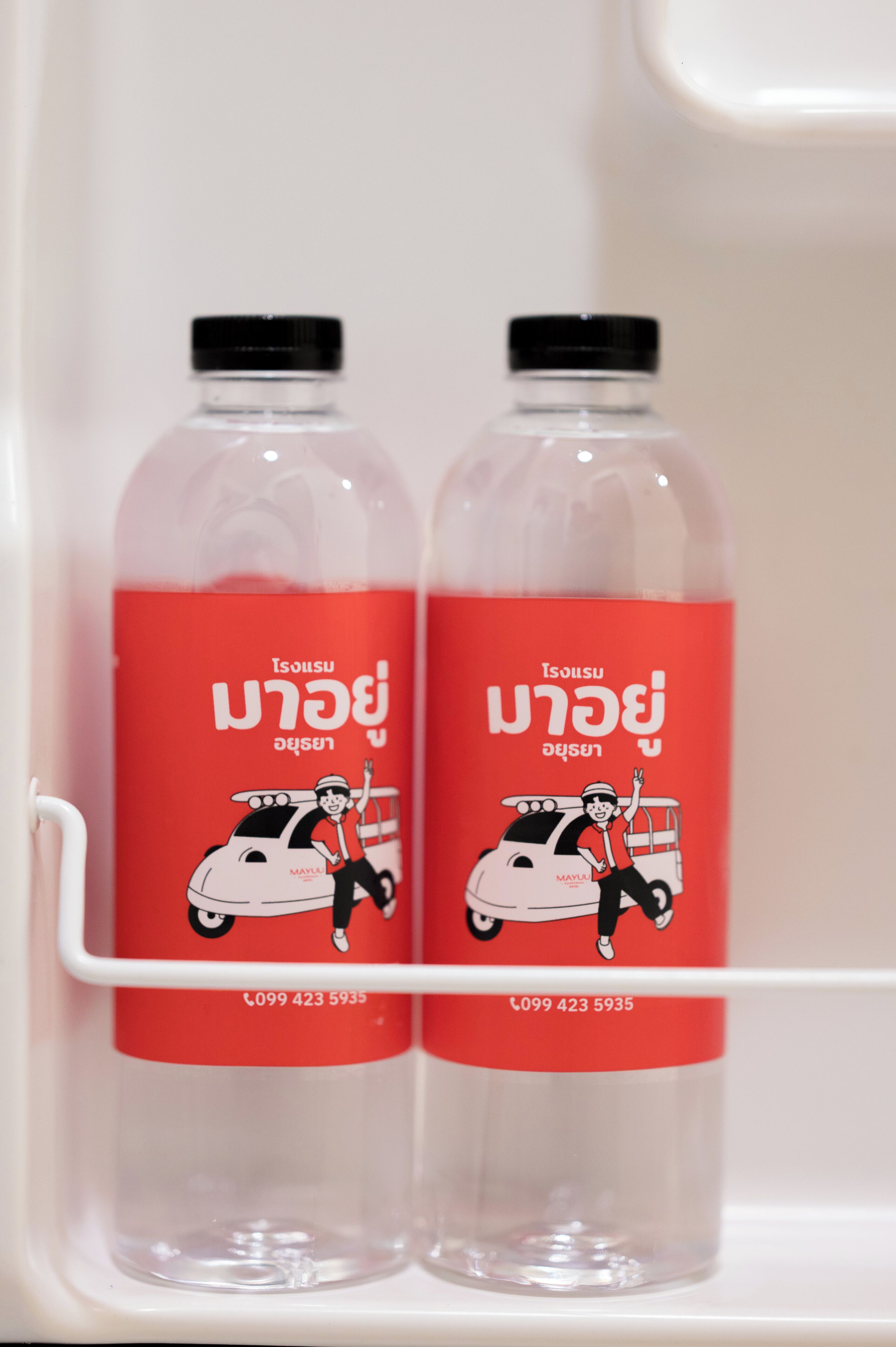 Dos botellas con etiquetas rojas y tapones negros dentro de un refrigerador.