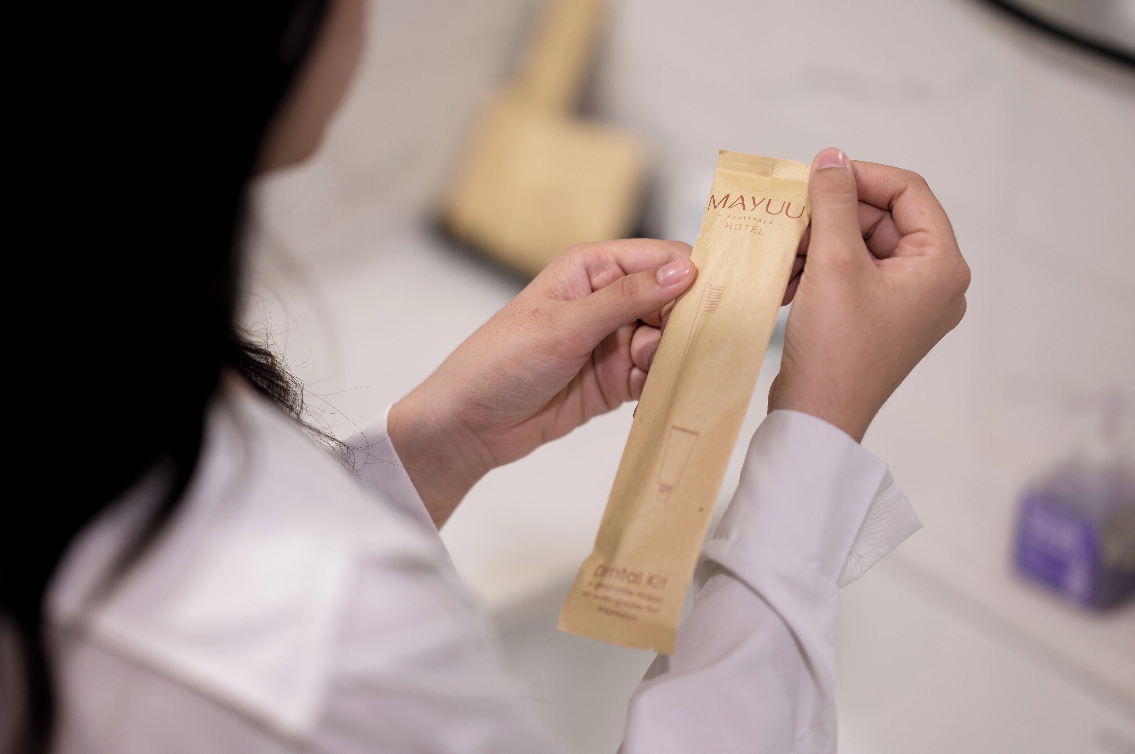Una persona sosteniendo una bolsa de papel marrón con la leyenda 'MAYU HOTEL'.