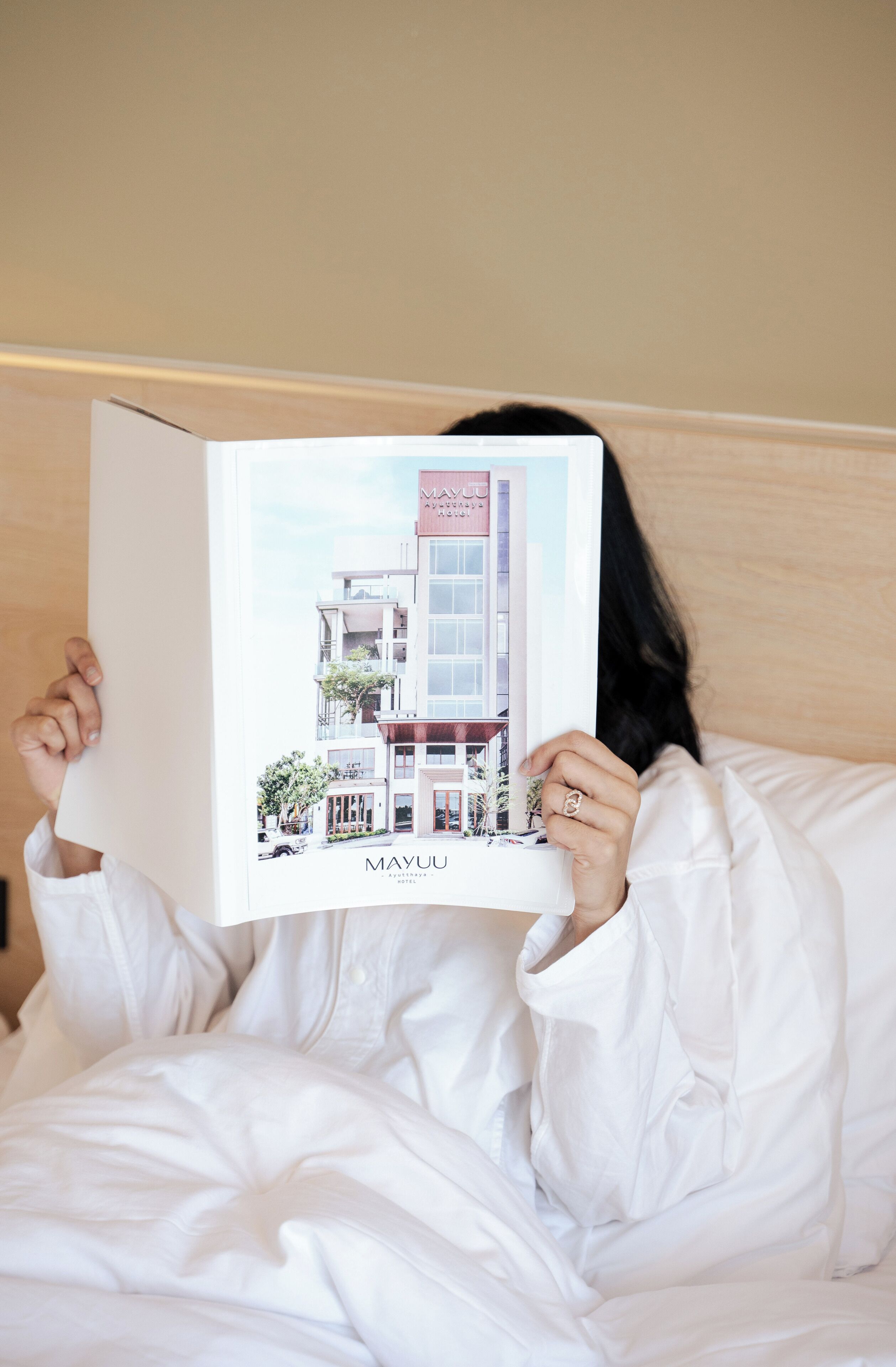 Una persona sosteniendo un libro con una ilustración de un edificio titulado “MAYUU”.