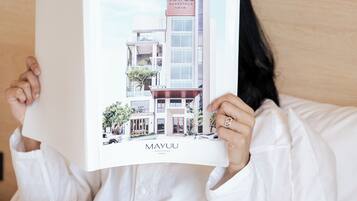Una persona sosteniendo un libro con una ilustración de un edificio titulado “MAYUU”.