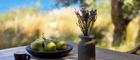 A wooden table with a bowl of green apples, a cup, and a book.