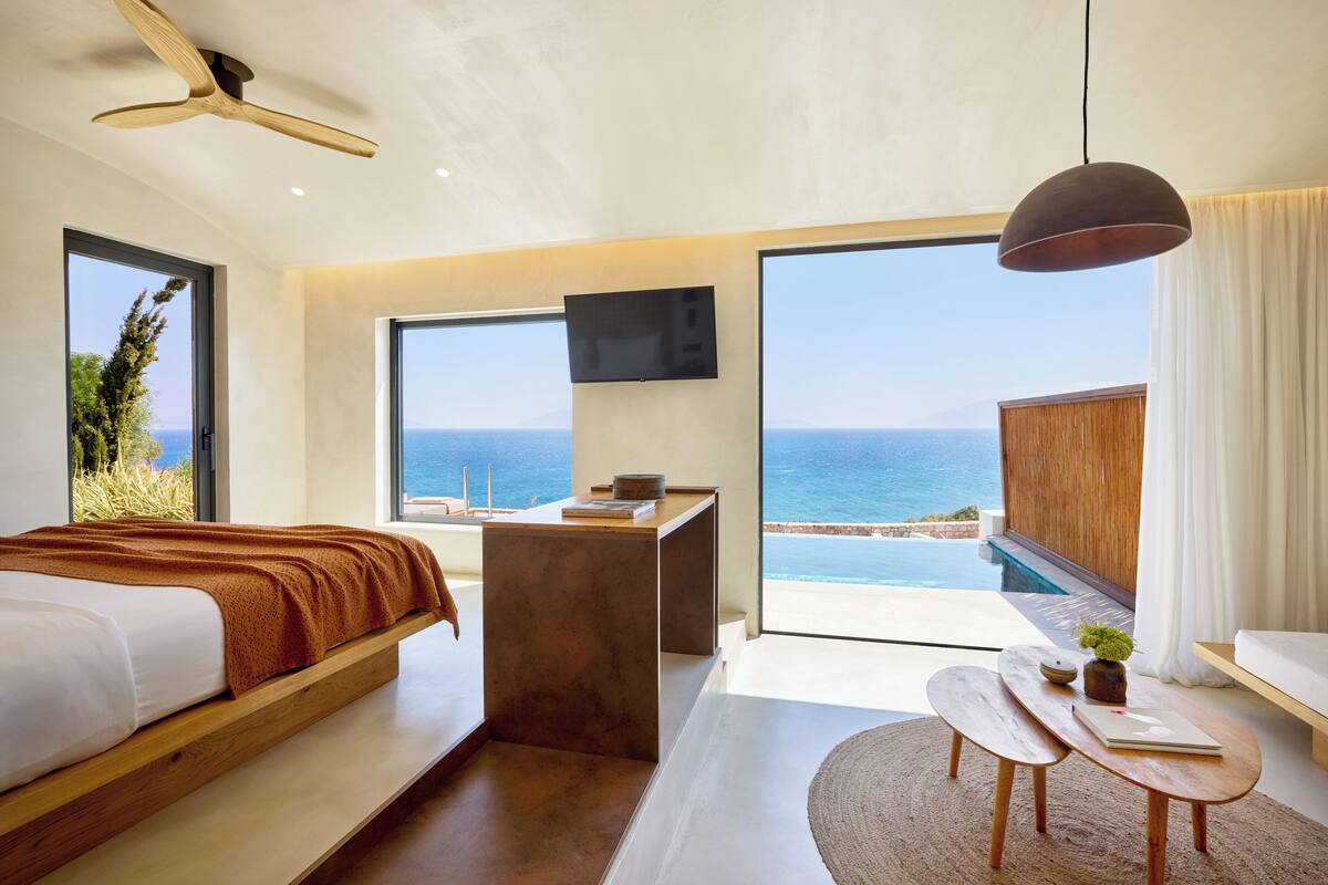 Un dormitorio moderno con cama, escritorio y vista al océano.