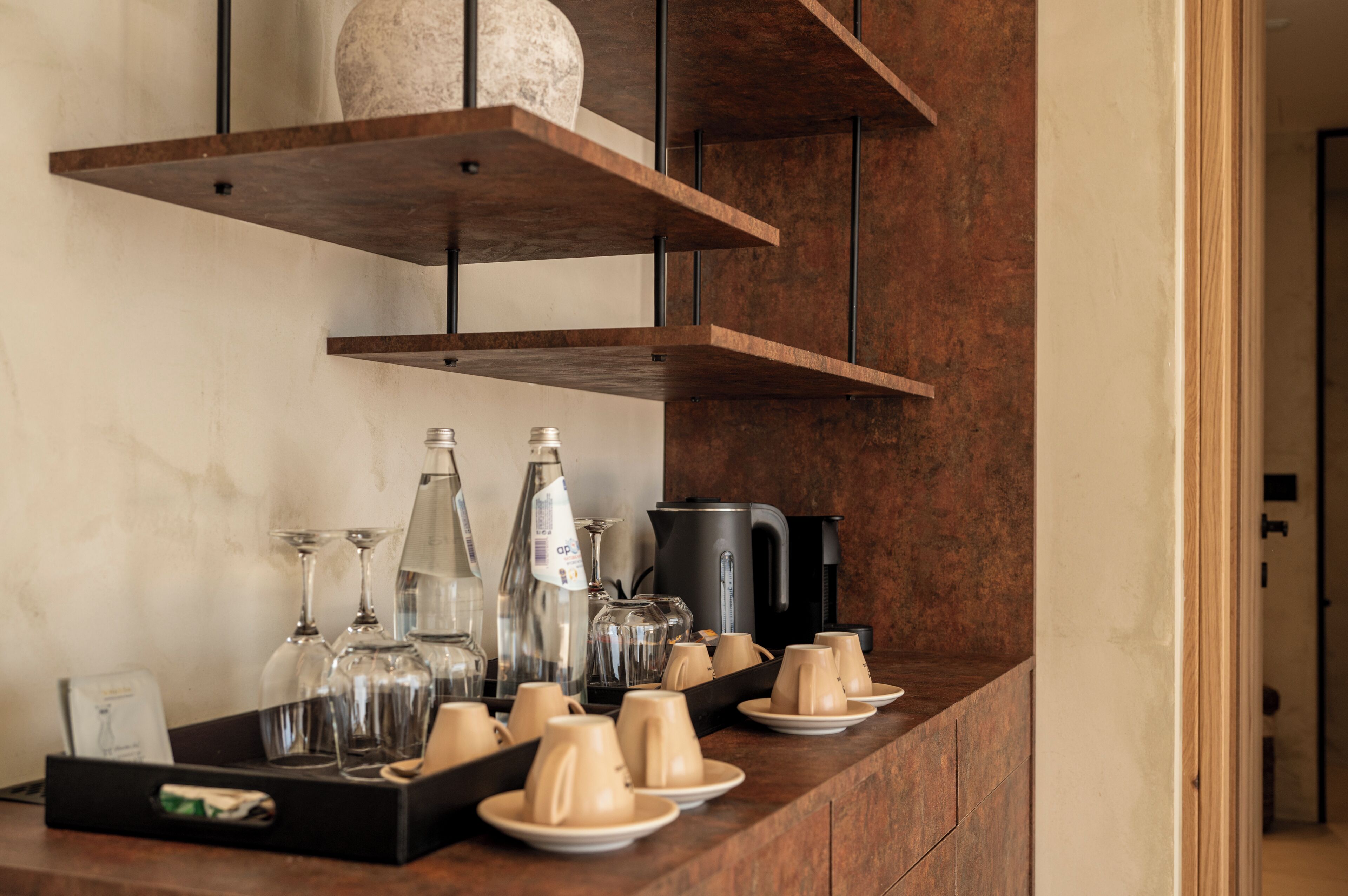 A bar area with shelves, glasses, and a coffee machine.