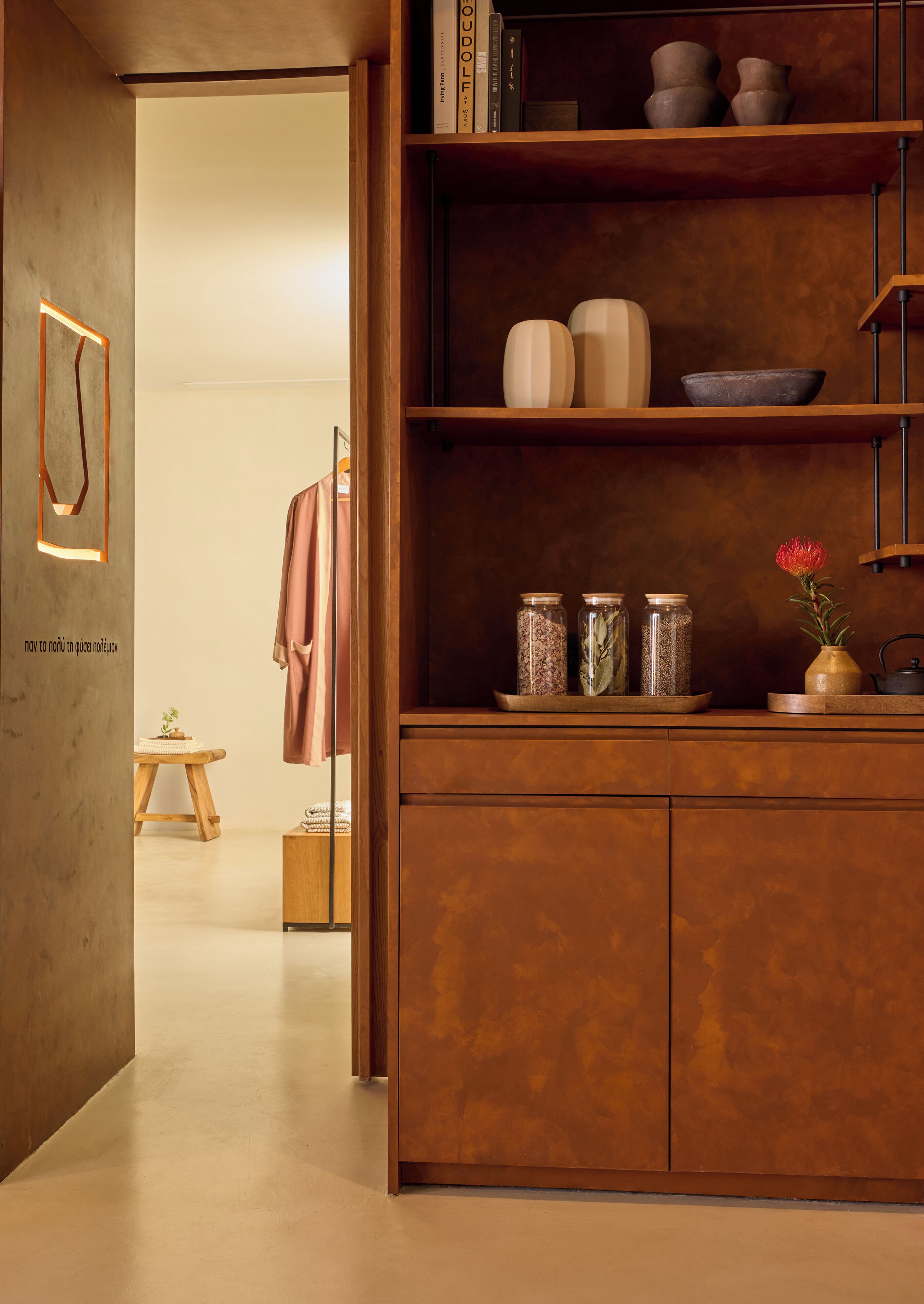 Un interior moderno con un armario de madera, estantes con objetos decorativos y una prenda colgando.