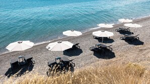 A beach with umbrellas and lounge chairs, a clear view of the sea, and distant mountains. - KOIA All - Suite Well Being Resort - Adults Only (Kos)