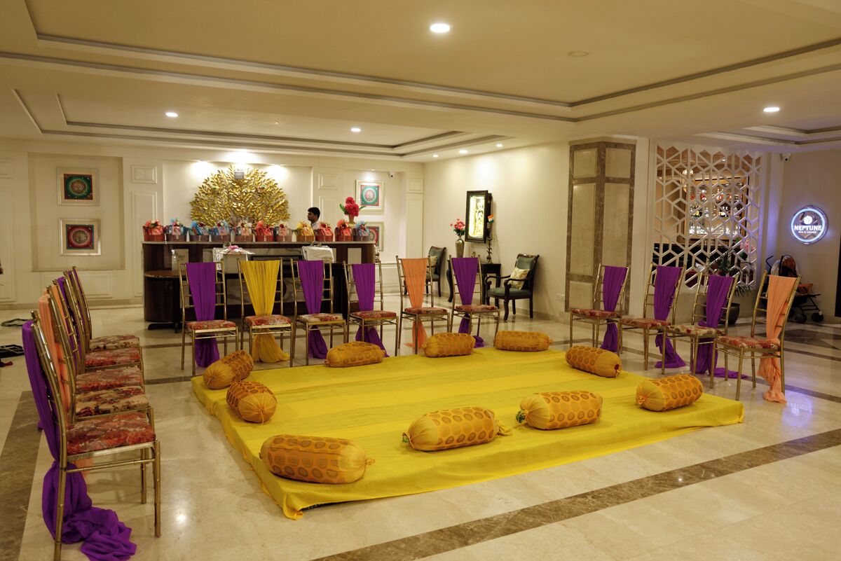 A hotel lobby with a reception desk, chairs, and a large yellow carpet with pillows.