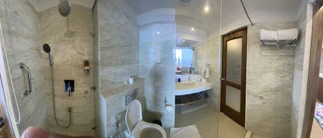A bathroom with a shower, toilet, sink, and towel rack.