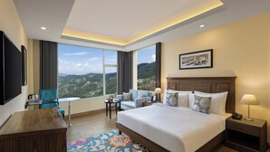 A hotel room with a large bed, a desk, a chair, and a view of the mountains. - Fortune Park Kufri, Shimla - Member ITC Hotels' Group (Theog)