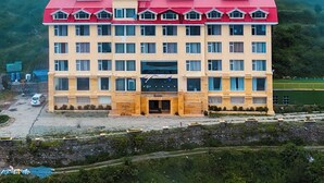 A multi-story building with a red roof, surrounded by a mountainous landscape and enveloped in mist. - Fortune Park Kufri, Shimla - Member ITC Hotels' Group (Theog)