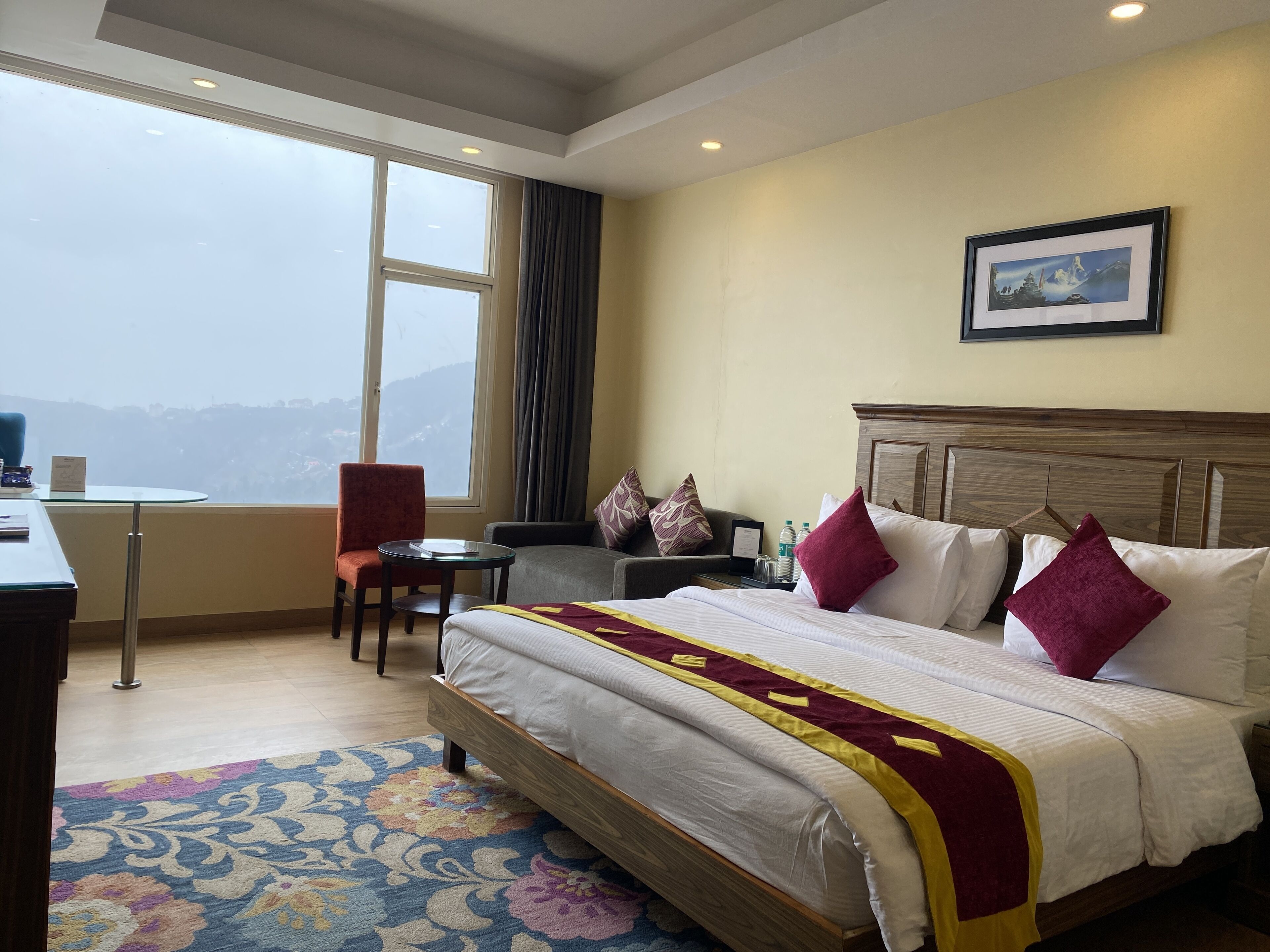 Ein Hotelzimmer mit einem großen Bett, einem Schreibtisch, einem Stuhl und Blick auf die Berge.