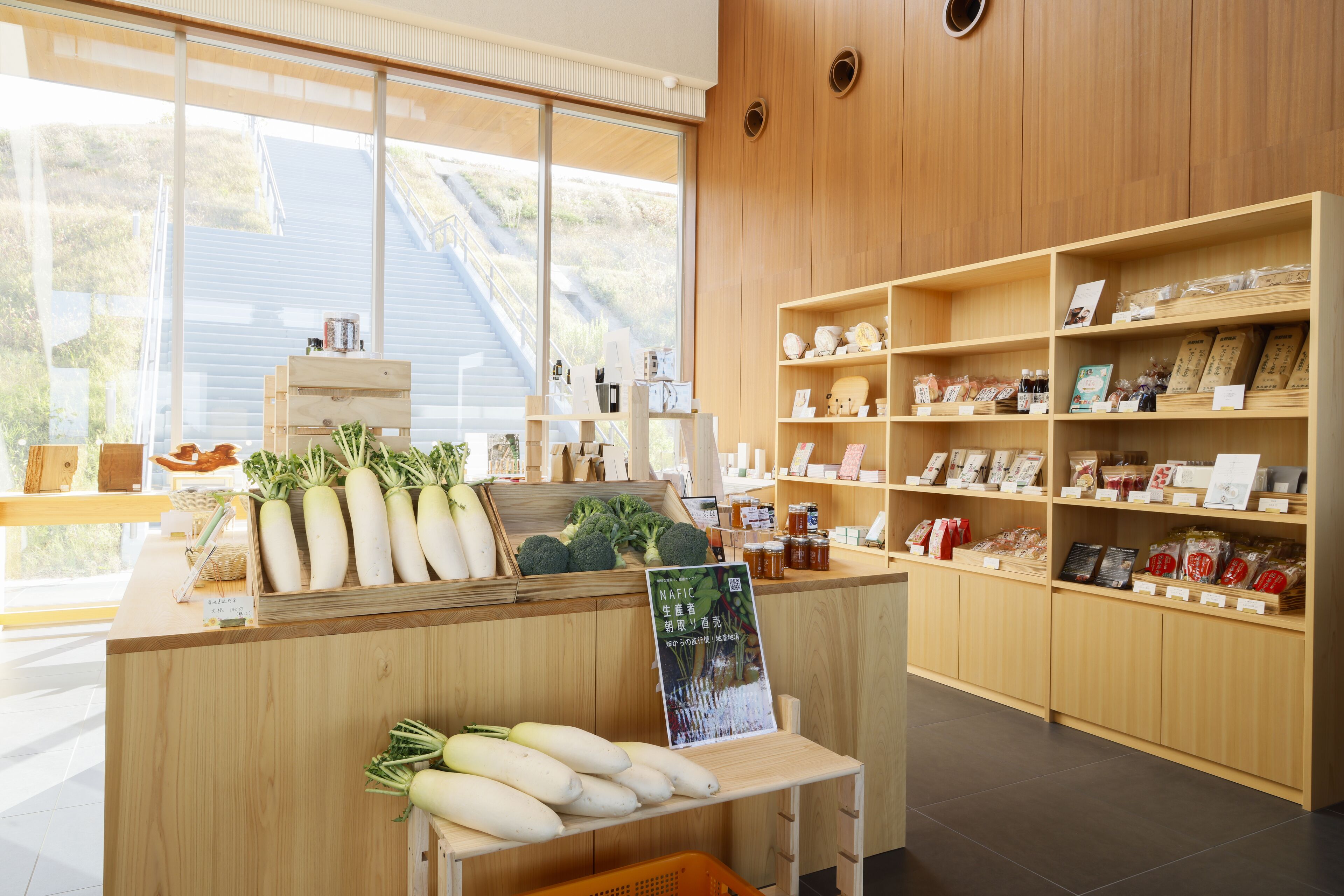 Interior de una tienda con estantes de madera, una exhibición de verduras frescas y un cartel.