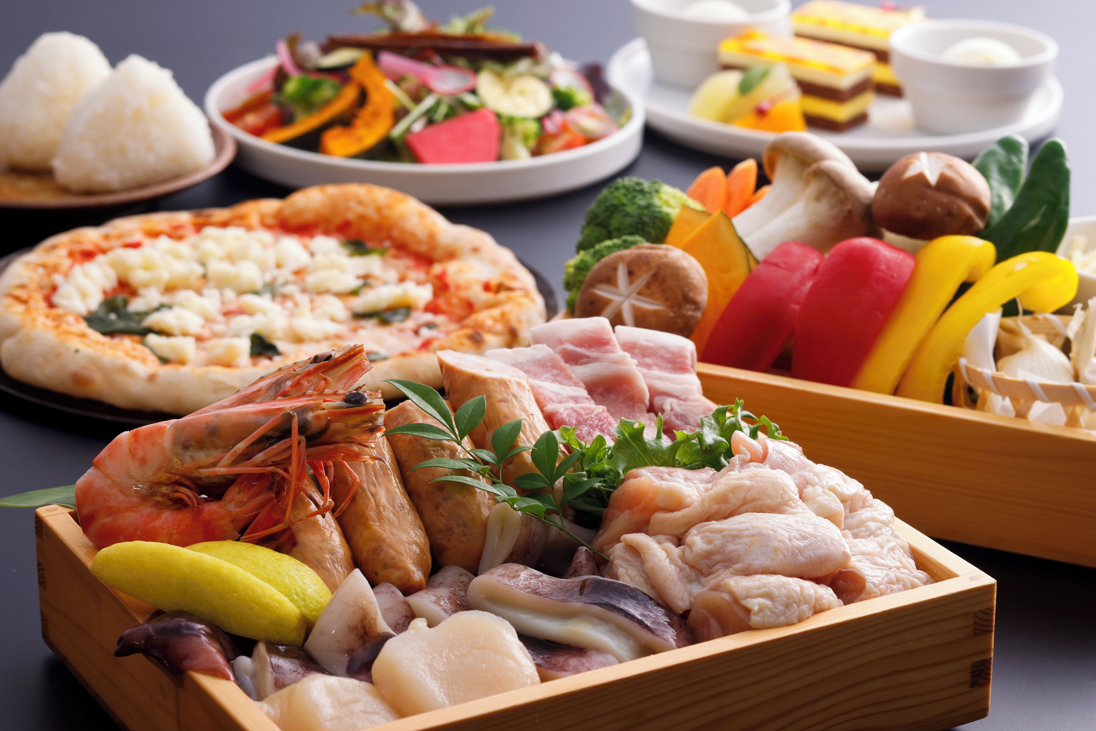 A variety of dishes including seafood, vegetables, and a pizza.