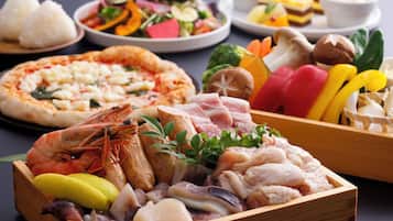 A variety of dishes including seafood, vegetables, and a pizza.