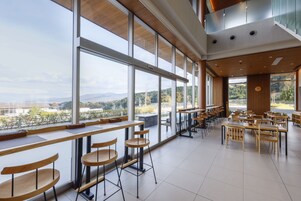 Un café espacioso con amplias ventanas que ofrecen vistas al exterior.