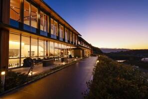 Un hotel moderno con amplios ventanales, mobiliario exterior y vistas al paisaje.